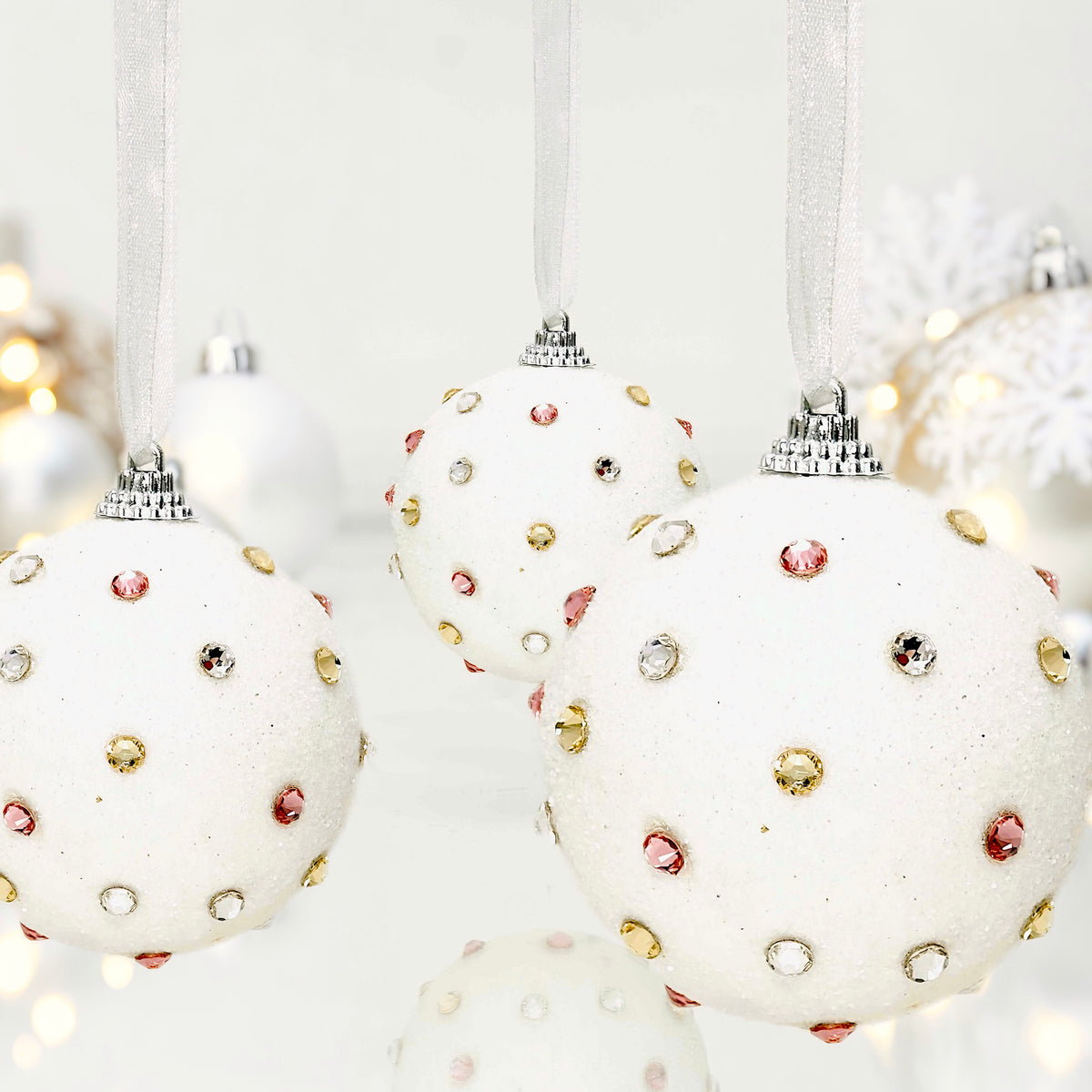 Christmas snowball ornaments with clear, gold and pink crystals in glam setting