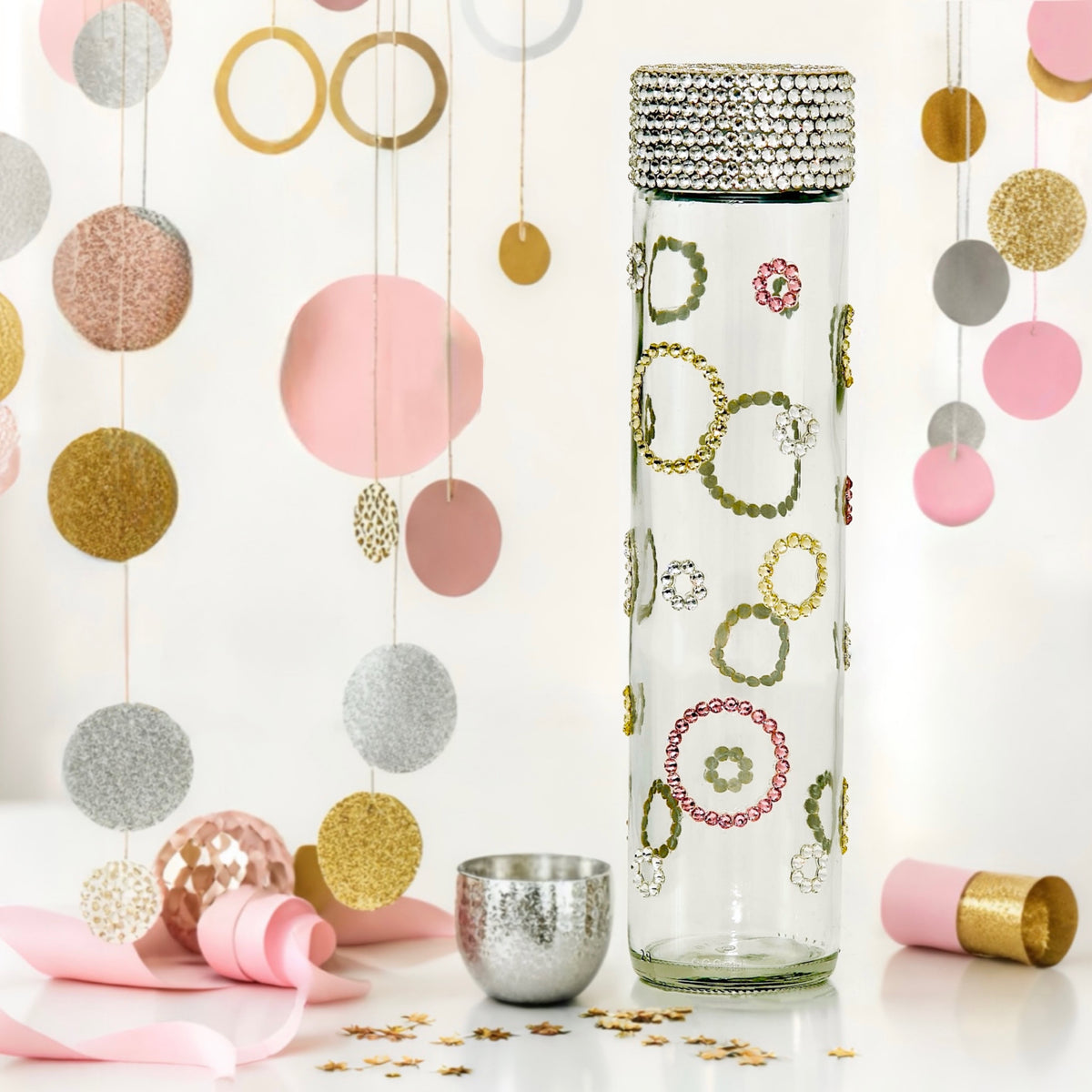 Colorful hoops clear glass water bottle with gold, pink and silver crystal hoops in party setting